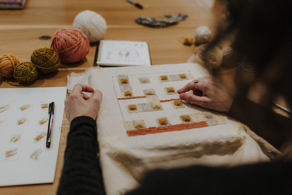 Kristen Dettoni working on punch needle art piece with natural dyed yarn.