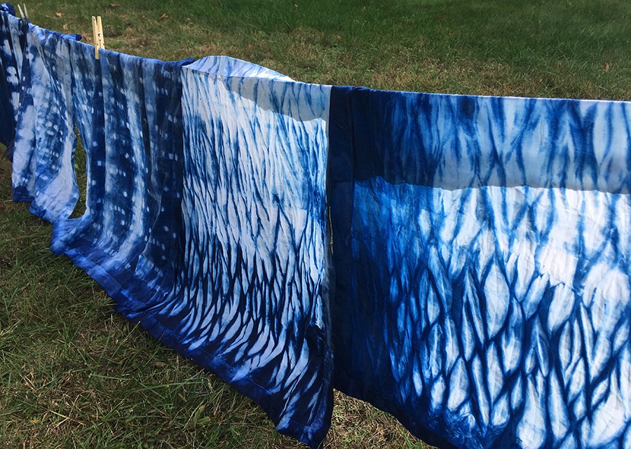 Examples of indigo dyed shibori fabrics hanging to dry.