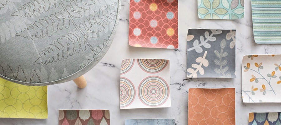 Birds Eye view of stool and fabric swatches on floor.|Five swatches of pattern designs in a flat lay with embroidery hoop