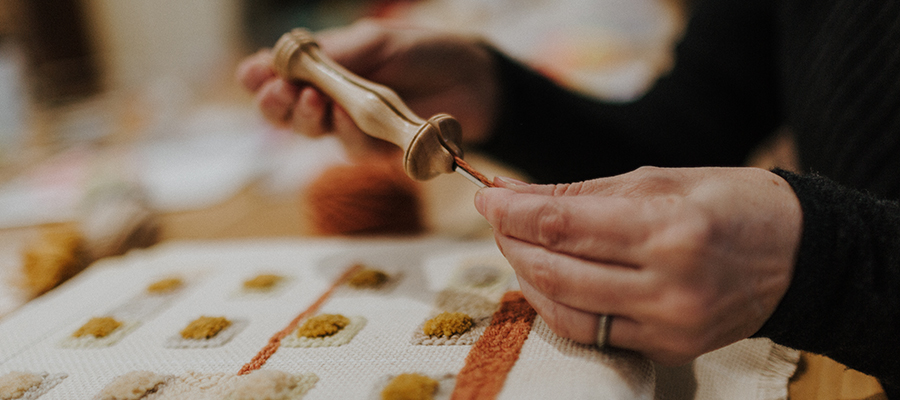 Photo of Kristen Dettoni working on a punch needle art piece.|Photo by Kristen Dettoni's original punchneedle art piece