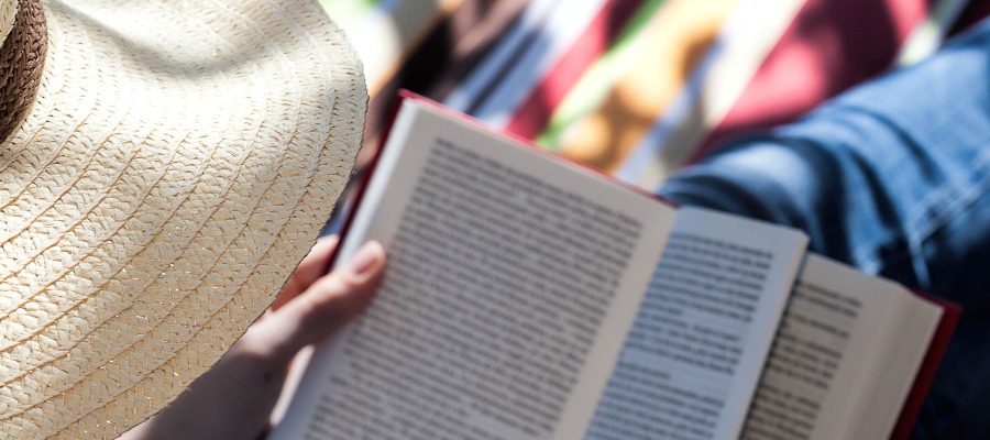 Looking over the shoulder of a person reading. You can see the brim of a straw hat