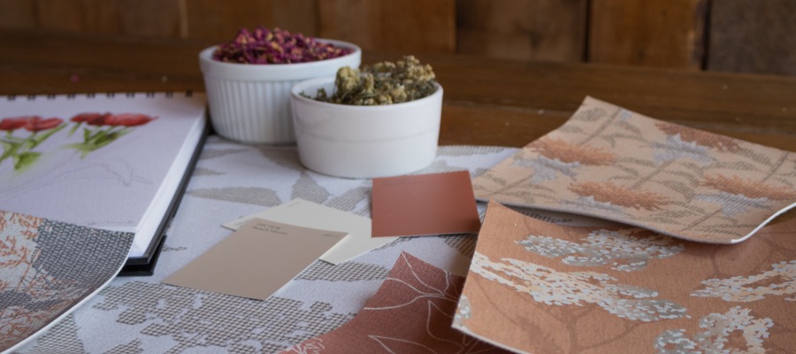 Fabric swatches on a table with ramekins of herbs and a sketchbook.|||Design Poll pattern Rose with color chips from Sherwin-Williams.