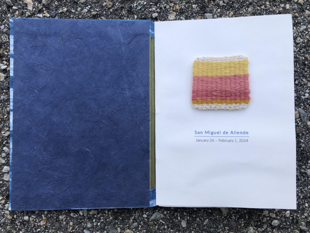 Photo of a travel journal opened with a title page that has a handwoven swatch by Kristin Crane and the words San Miguel de Allende and the date of the trip. 