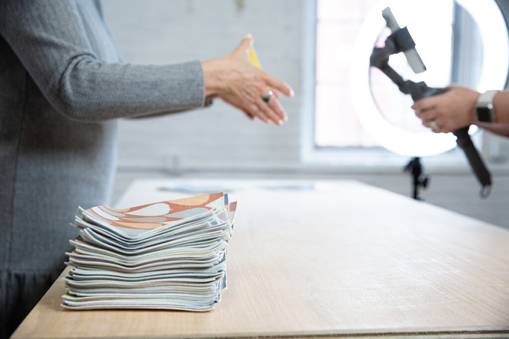 Kristen Dettoni recording a video with a pile of Design Pool swatches next to her.